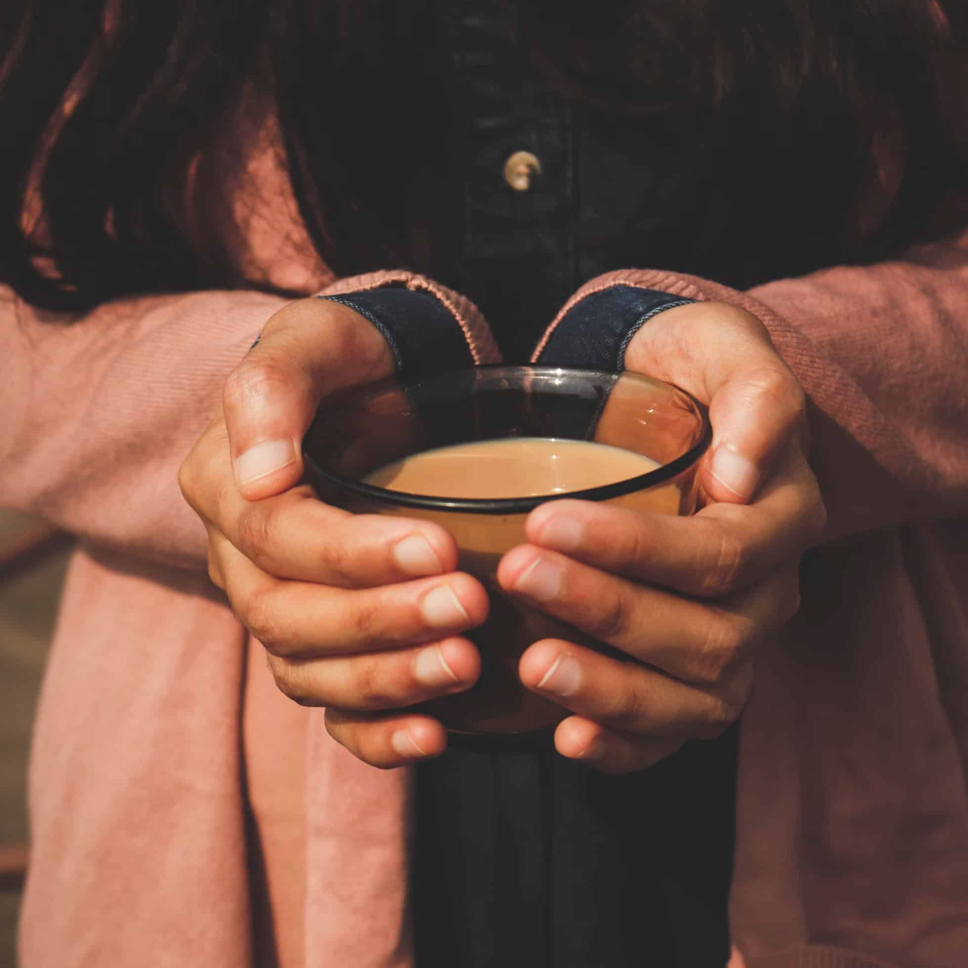 Hands cradling a warm drink in soft light